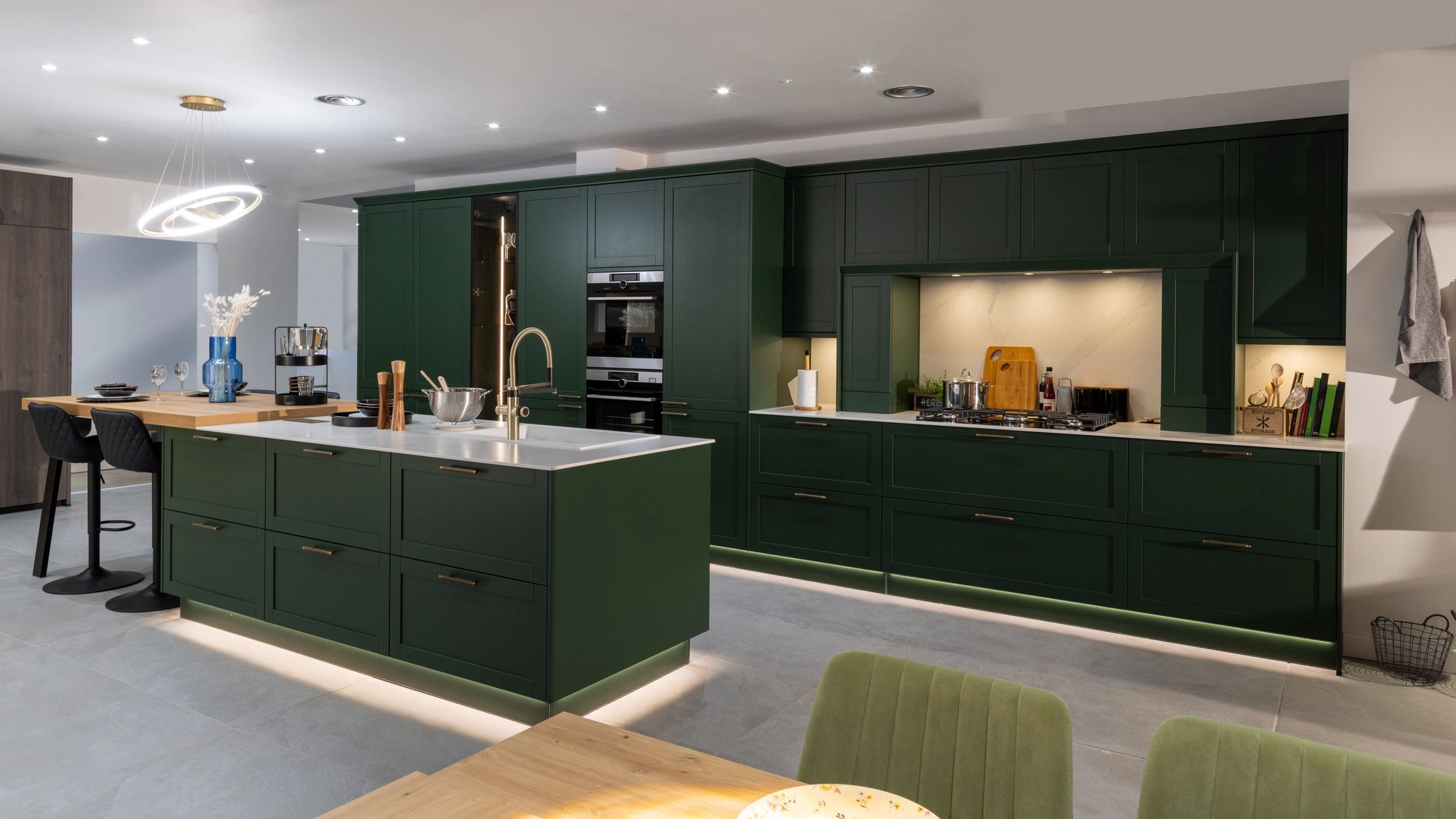 Elegant luxury kitchen with green cabinetry, brass accents, and a bright island